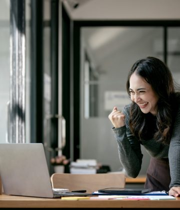 Beautiful Asian woman celebrate with laptop, successful business startup small business concept.